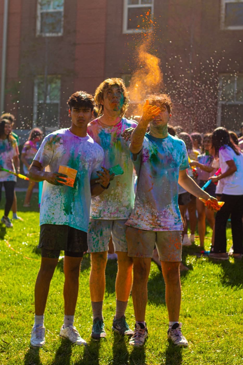 Friends covered in colored powder on a campus lawn
