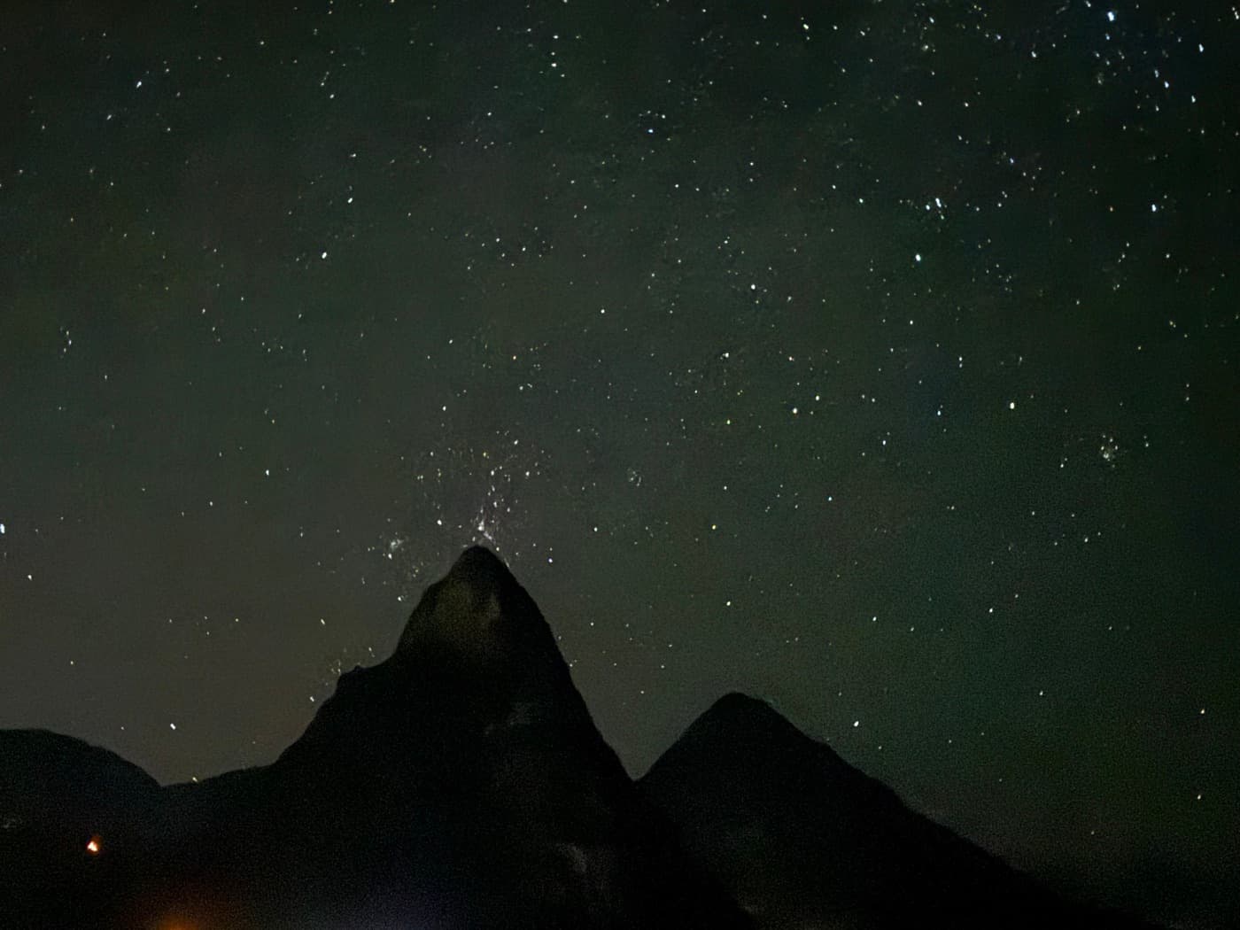 A star-filled night sky over two dark mountain peaks
