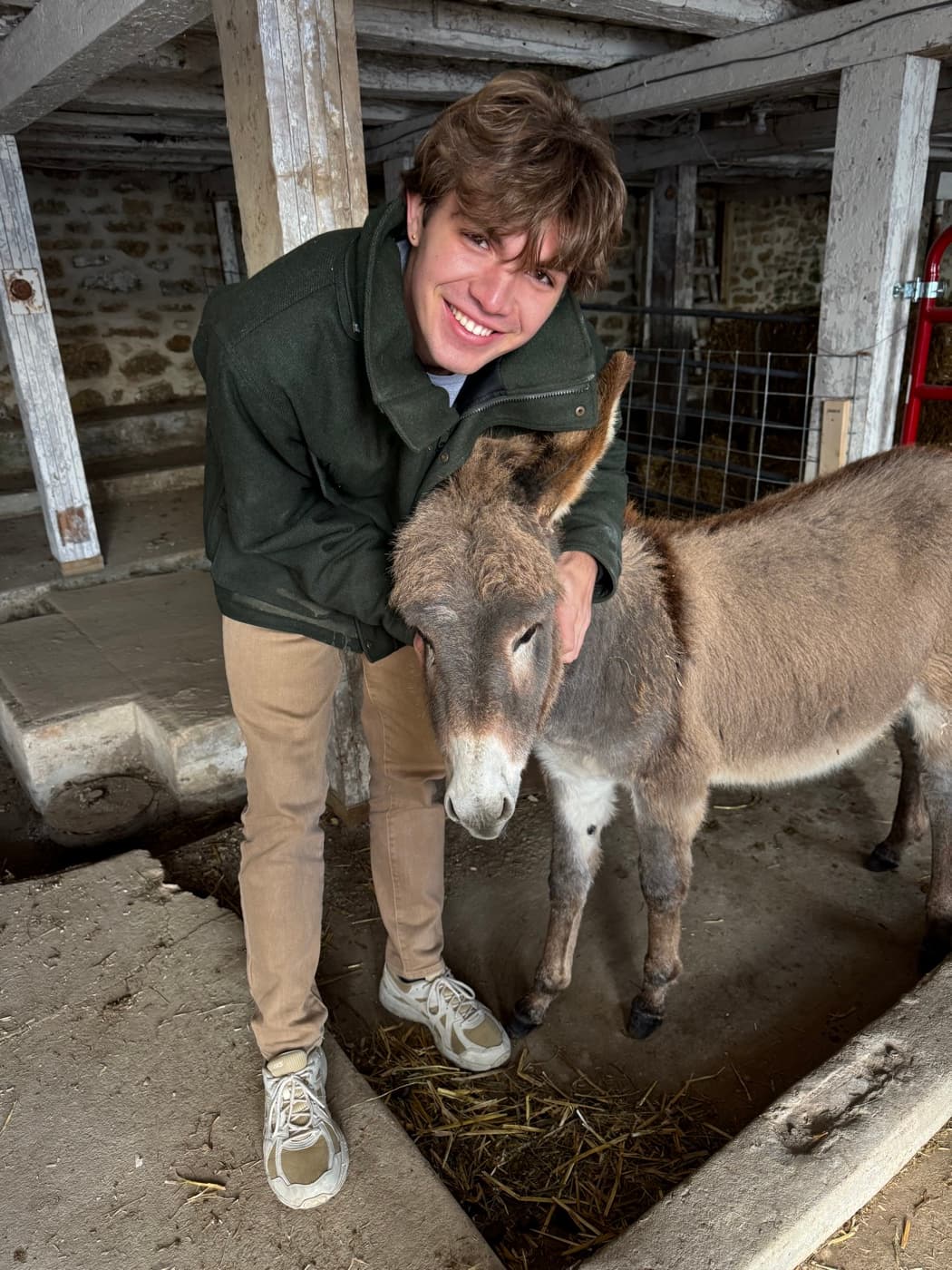 Sam smiling while petting a donkey inside the barn